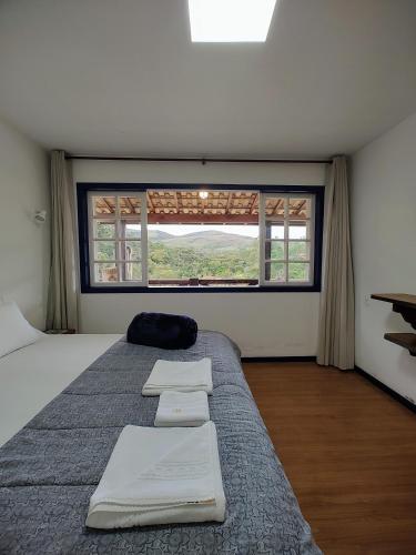 a bedroom with a bed with two towels on it at Recanto Serra do Trovão in Ouro Preto