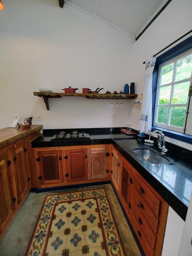 a kitchen with wooden cabinets and a sink and a rug at Recanto Serra do Trovão in Ouro Preto