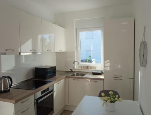 a kitchen with white cabinets and a sink and a window at Apartman Punta Radman in Petrcane