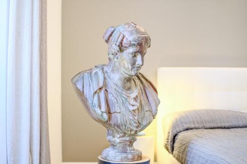 a statue of a bust on a table next to a bed at Dolcevita Boutique Apartment in Florence