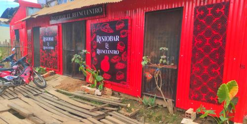 czerwony budynek z motocyklem zaparkowanym przed nim w obiekcie EL REENCUENTRO w mieście Pucallpa
