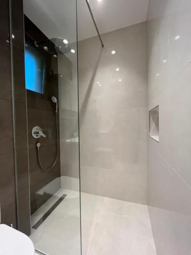 um chuveiro com uma porta de vidro na casa de banho em Perla apartmani em Petrovac na Moru