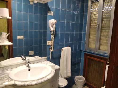 a blue tiled bathroom with a sink and a shower at Restaurante & Hostal El Volante in Moraleja