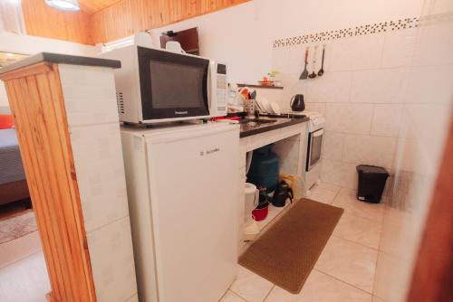 a small kitchen with a microwave on top of a refrigerator at Chalé das Carpas in Penedo