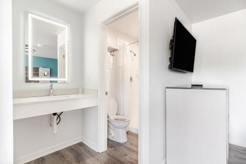 a bathroom with a sink and a toilet and a tv at Blue Beach Motel Providence North Kingstown in North Kingstown