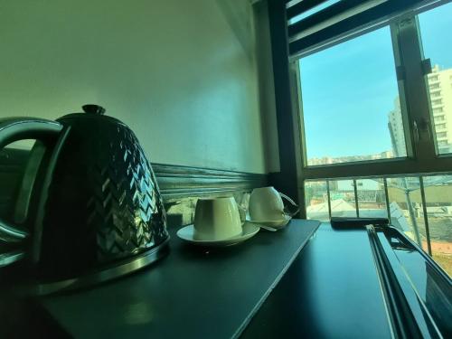 a tea kettle and plates on a table with a window at Hotel Asturias in Viña del Mar