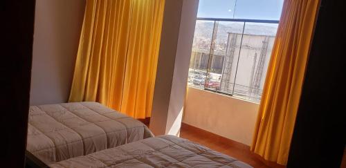 Habitación con 2 camas y ventana con cortinas amarillas. en A un minuto del aeropuerto Siéntase como en casa, en Cusco