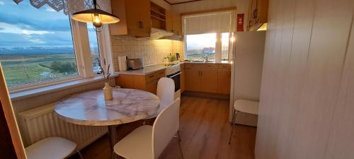 una pequeña cocina con mesa, sillas y ventana en Guesthouse Klambrasel, en Skogar