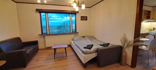 uma sala de estar com um sofá, uma mesa e uma janela em Guesthouse Klambrasel em Skogar