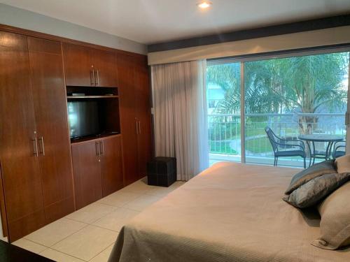 1 dormitorio con 1 cama grande y puerta corredera de cristal en Condominio c/ alberca y vista a Marina Mazatlán, en Mazatlán