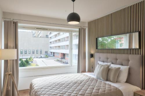 um quarto com uma cama e uma grande janela em Norden Homes Peaceful & Central Apt. Free Parking em Turku
