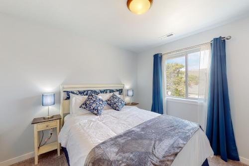 a bedroom with a bed with blue curtains and a window at Pelican and the Raven in Rockaway Beach