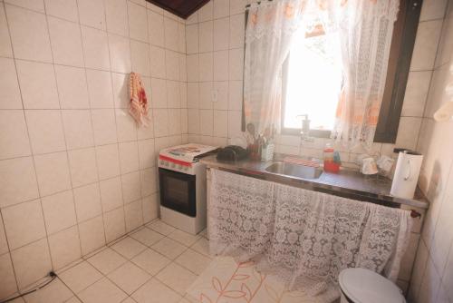 a small kitchen with a sink and a stove at Chalé das Carpas in Penedo