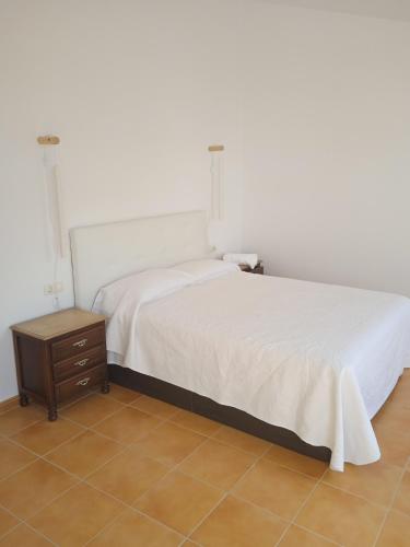 a bedroom with a white bed and a wooden nightstand at Villa Xunqueira 3 in Cee