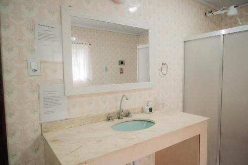 a bathroom with a sink and a mirror at Chalé das Carpas in Penedo