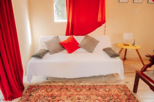 a white couch in a room with red curtains at Chalé das Carpas in Penedo