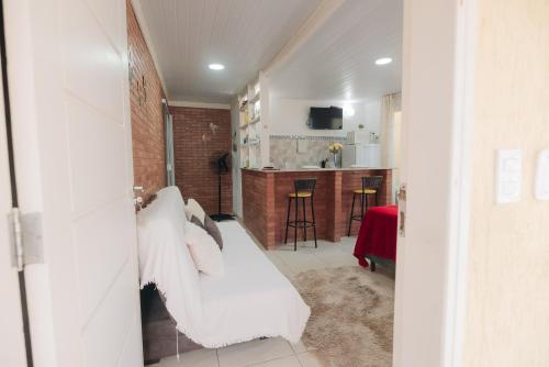 a living room with a white couch and a kitchen at Chalé das Carpas in Penedo