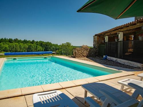 une piscine avec des chaises et un parasol dans l'établissement Gite Girou Haut, à Montcabrier