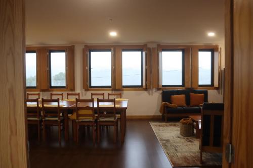 a dining room with a table and chairs and windows at Casa da Escola in Vouzela