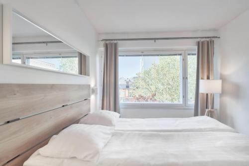 um quarto branco com uma cama grande e uma janela em Norden Homes Turku 2-Bedroom Nordic Apartment em Turku