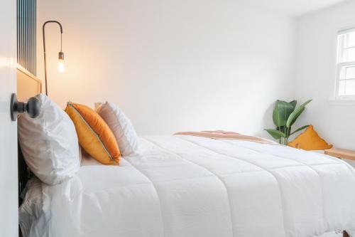 a white bed with orange pillows in a bedroom at Retro Retreat renovated 2BR, desk, no chore list! in Kingston