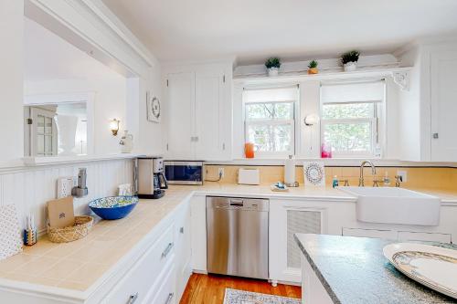 a white kitchen with white cabinets and a sink at Bees Knees House in Boothbay Harbor
