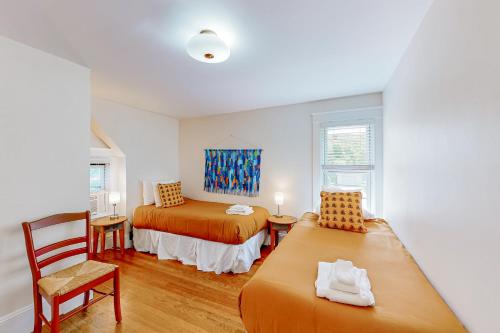 a bedroom with two beds and a table and a chair at Bees Knees House in Boothbay Harbor