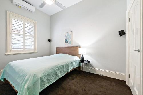 a white bedroom with a bed and a window at Azami - Charming Gilbert Cottage in Adelaide
