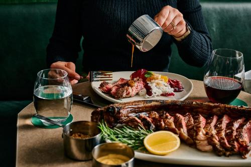 a person pouring sauce on a plate of food at Rydges Melbourne in Melbourne