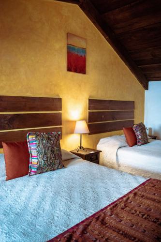 a bedroom with two beds and a table with a lamp at Hotel la Galería in Antigua Guatemala