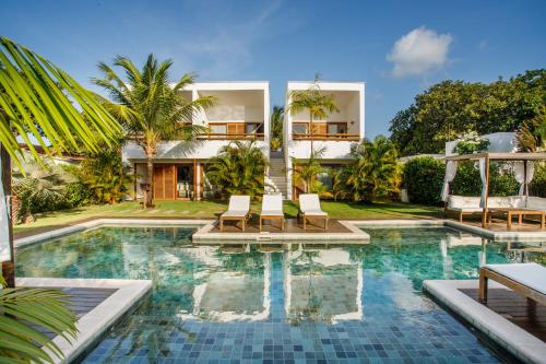 a villa with a swimming pool in front of a house at Portofino Pousada in São Miguel do Gostoso