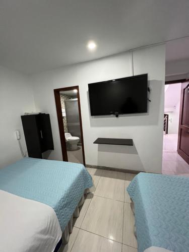 a bedroom with two beds and a flat screen tv at Hotel Tempus in Pasto