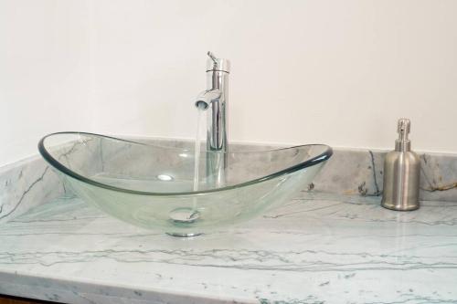 a glass sink with a faucet on a counter at Enclave Villa V3 -Overlooking Pitons & Ocean ! Wow in Soufrière