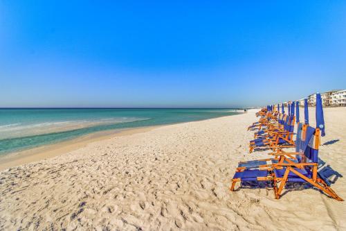 a row of beach chairs sitting on the beach at Luau 7010 in Destin