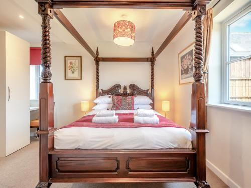 Cette chambre comprend un lit à baldaquin et une fenêtre. dans l'établissement The Farmhouse, à Ferndown