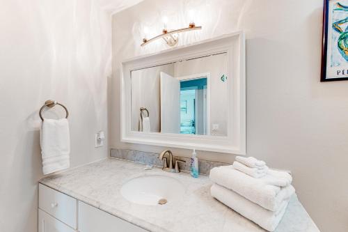 a white bathroom with a sink and a mirror at Flood Reef Retreat - Blue Crab Cottage in Pensacola