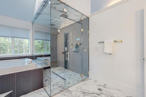 a bathroom with a glass shower and a tub at Webb River House in Rumford