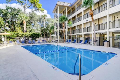 a swimming pool in front of a building with chairs and trees at Sea Side Villas 108 in Hilton Head Island