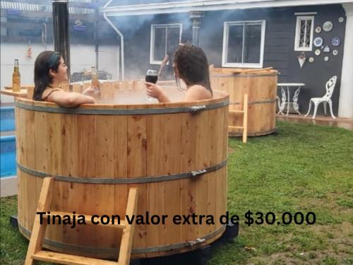 two women in a barrel hot tub in a yard at Habitación 1 casa/tinaja/piscina in Valdivia