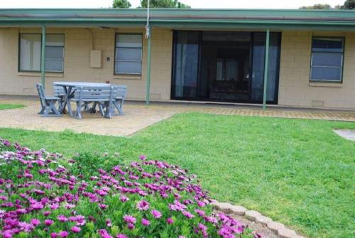 a picnic table in front of a house with flowers at Dun Workin - Absolute Beachfront in Coobowie