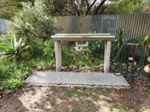 a wooden bench sitting on a grate in a garden at Dun Workin - Absolute Beachfront in Coobowie