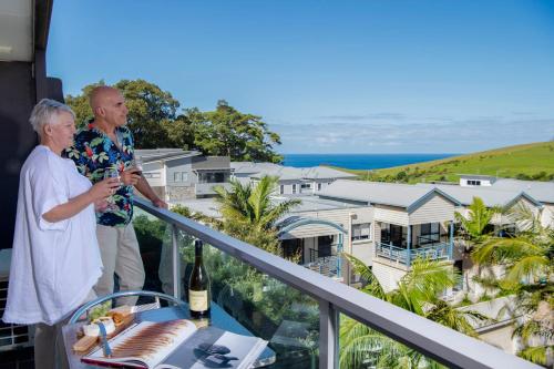 a man and woman standing on a balcony with a bottle of wine at Park Ridge Retreat in Gerringong