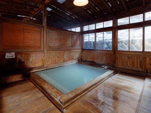 an indoor hot tub in a wooden room with windows at Ryokan Tamagoyu in Machi-niwasaka