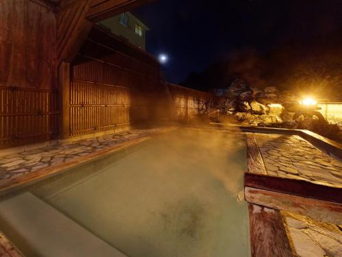 a pool of water at night with a building at Ryokan Tamagoyu in Machi-niwasaka
