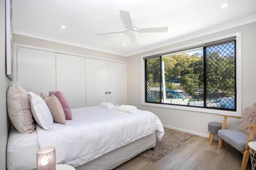 a bedroom with a white bed and a window at Renovated Coastal getaway with water views in Umina