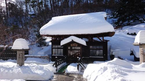 a small building with snow on top of it at Ryokan Tamagoyu in Machi-niwasaka