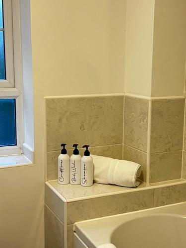 tres botellas sentadas en un estante junto a una bañera en Comfy 2-bed home - Contractors and Leisure en West Bromwich