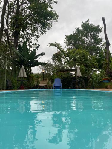 a large blue swimming pool with trees in the background at Pequeno Paraíso in Foz do Iguaçu