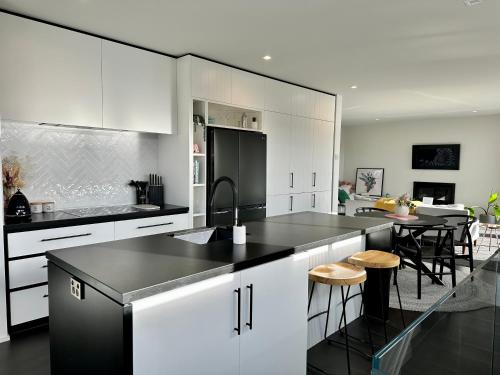 a kitchen with white cabinets and a black counter top at Homestead Retreat - 2 Bedroom - Lake View in Queenstown