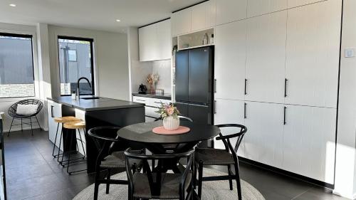 kuchnia ze stołem z krzesłami i czarną lodówką w obiekcie Homestead Retreat - 2 Bedroom - Lake View w mieście Queenstown